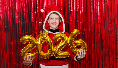 Happy Santa welcomes the New Year 2026 against a red tinsel background. Holiday concept.