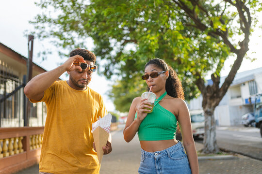 Young couple walking together, enjoying drinks on a sunny day