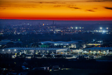 Sonnenuntergang über der Stadt mit beleuchteten Industriegebieten und einem klaren Himmel