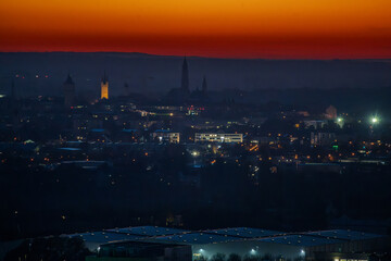 Fototapeta premium Blick auf die Stadt bei Abenddämmerung mit leuchtenden Lichtern und Silhouetten der Gebäude