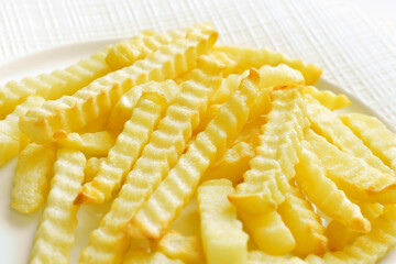 Crinkle cut fried potato french fries chips on a plate.
