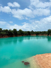 Clear turquoise water reflects clouds and trees.
