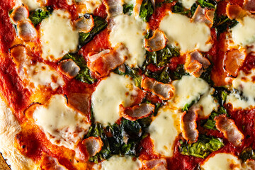 Pizza with bacon, tomatoes, spinach and cheese, close-up. Pizza textured background.