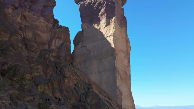 A dramatic and scenic view of the iconic Monkey Face rock pillar, a unique volcanic tuff formation, standing tall within the rugged landscape of Smith Rock State Park on a bright summer day.