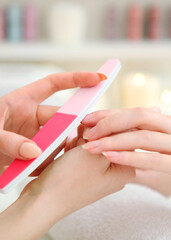 Closeup shot of a woman in a nail salon getting a manicure. Vertical photo format
