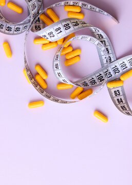Measuring tape and diet pills on a colored background close-up.. Vertical photo format. 