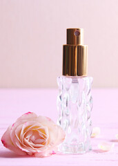 Perfume bottle and rose flowers on a light background close up. Vertical photo format