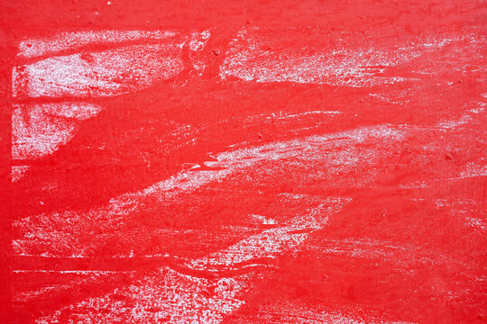 Rough red wall with scraped white paint marks and textured surface. Abstract distressed background and worn painted texture. Copy space