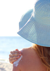 Young woman on the beach uses sunscreen.. Vertical photo format