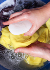A woman washes clothes with her hands in soapy water. Hand wash clothes. . Vertical photo format