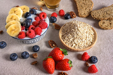Full bowl of berries and banana slices in milk/yogurt, served with a side of raw oats on a light counter. Perfect for high-fiber, healthy, plant-based breakfast concepts