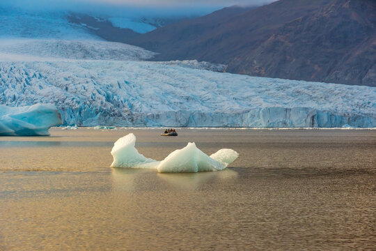 Fjallsarlon glacial lagoon showcases icebergs floating in calm waters, reflecting the soft twilight glow against the massive glacier backdrop. An iconic location in Iceland