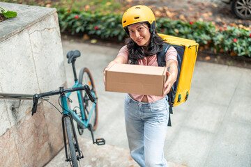 Asian woman delivering package by bicycle wearing helmet