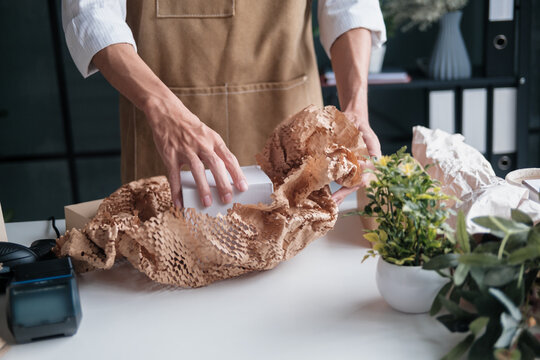 startup entrepreneur packs online order in recyclable cardboard box for eco-conscious customer - Powered by Adobe