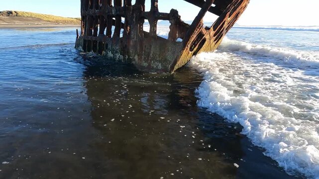 A poignant view of the rusted skeletal remains of the Peter Iredale shipwreck, standing sentinel on the sandy beach within Fort Stevens State Park on the Oregon Coast.