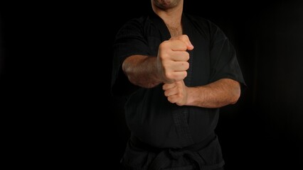 A martial artist demonstrates a punch in a black uniform, showing focus and strength against a dark background. A man conducts training in the Chinese martial art of Wing Chun.