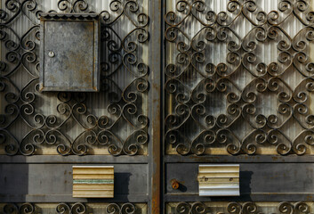 Ornate iron gate with mailbox and rusty vintage design