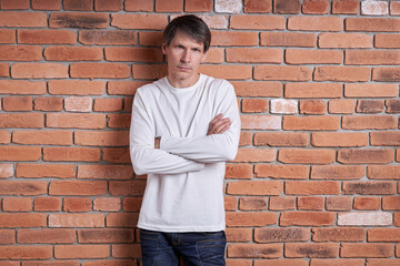 Portrait of a middle-aged European man in a white shirt near a brick wall