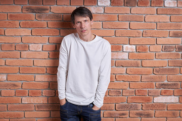 Portrait of a middle-aged European man in a white shirt near a brick wall