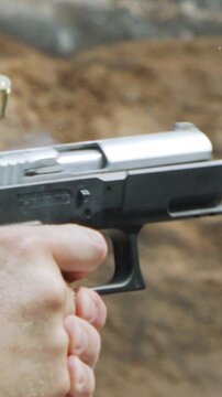 Slow motion of a hand gun firing in a firing range with cartridge flying away