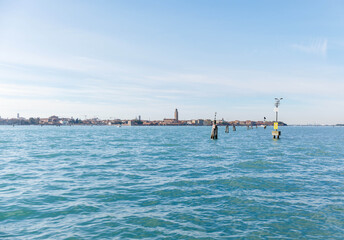 Murano, Italy - November 21, 2024: Scenic view of Murano Island with clear blue waters and distant buildings, showcasing the beauty of Venetian architecture and tranquil atmosphere