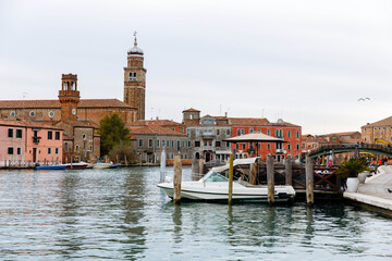 Murano, Italy - November 21, 2024: Scenic view of Murano Island with colorful buildings, boats on the water, and a historic bell tower, capturing the essence of Venetian charm and beauty