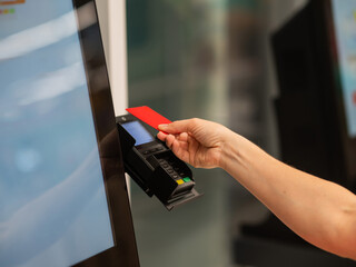Woman paying with credit card at self-checkout. 