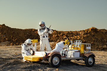 Two astronauts work on a modified go-kart in a dusty terrain under clear blue skies during the day