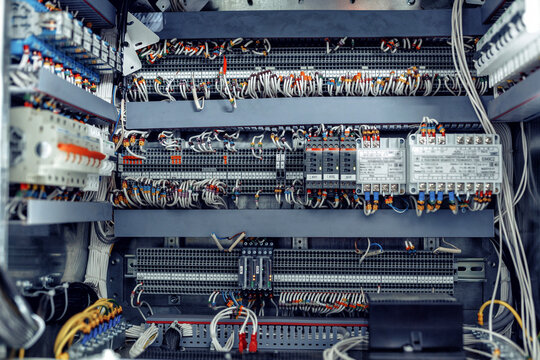 Intricate electrical control panel featuring numerous wires, connectors, and circuit components, showcasing the complexity of modern technology and industrial design with copy space - Powered by Adobe