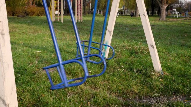 side view of an empty children's swing without seats swings by inertia