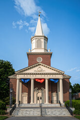 Historic Rooke Chapel with white steeple and brick facade under blue sky