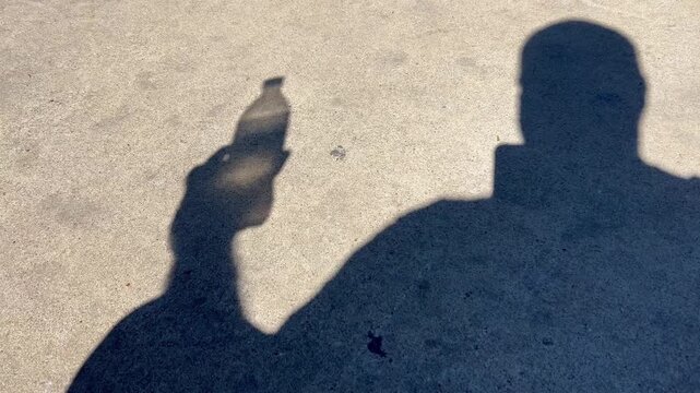 Man in shadow drinking a soda water in silhouette

