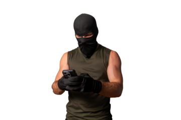 Masked cyber criminal wearing balaclava and gloves using smartphone for digital fraud and hacking activities