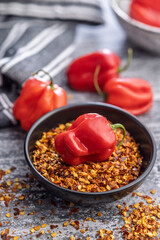 Red chili pepper habanero and chili flakes in bowl on kitchen table.