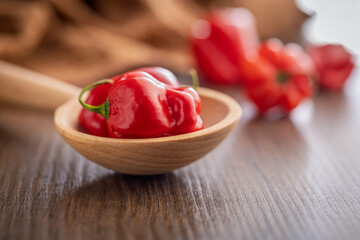Red chili pepper habanero on wooden spoon on wooden table.