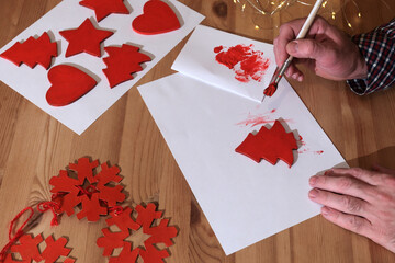 Person painting red christmas tree or winter holiday. preparing for the new year