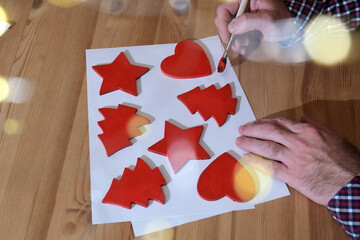 Person painting red christmas holiday decorations, preparing for the new year