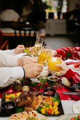 Family and friends clinking glasses at festive Christmas dinner celebration together