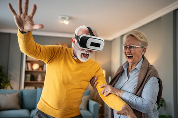 Senior man experiencing virtual reality with wife laughing