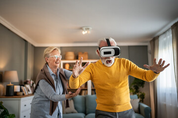 Senior couple enjoying virtual reality headset experience at home