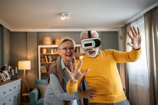 Joyful senior couple experiencing virtual reality technology at home - Powered by Adobe