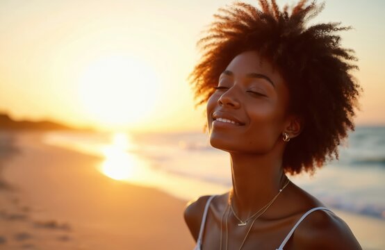 Black woman smiles with eyes closed on beach at sunset. Peaceful serene mood, golden hour light, ocean waves gently wash shore. Enjoying calm summer evening.