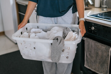 Laundry basket and coffee mug in a cozy home scene with a young woman in loungewear taking a break from housework; domestic life concept, candid indoor lifestyle background with copy space.