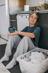 Laundry basket and coffee mug in a cozy home scene with a young woman in loungewear taking a break from housework; domestic life concept, candid indoor lifestyle background with copy space.