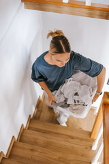 Laundry basket and coffee mug in a cozy home scene with a young woman in loungewear taking a break from housework; domestic life concept, candid indoor lifestyle background with copy space.