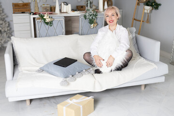 A woman in a white shirt is sitting on the bed. Winter New Year's decor
