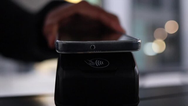 Person holding smartphone to make a contactless nfc payment at a pos terminal, fast secure mobile transaction at checkout in a modern retail environment, cashless commerce