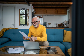 Senior man reviewing financial documents at home