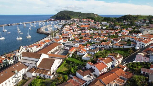 AZORES - 10.27.2025 - Beautiful aerial footage moving along the cost of Horta on Faial Island, where small boats are docked.