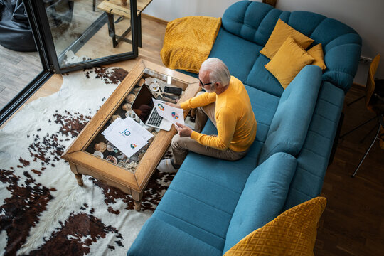 Senior man working remotely from home living room